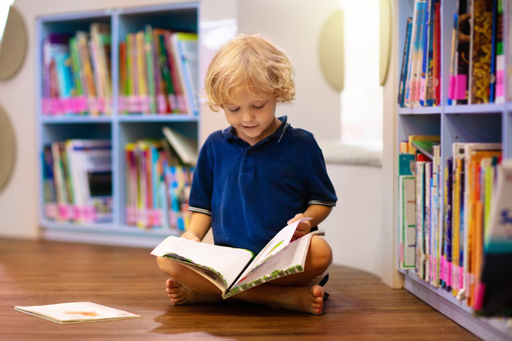 Child in school library. Kids reading books.