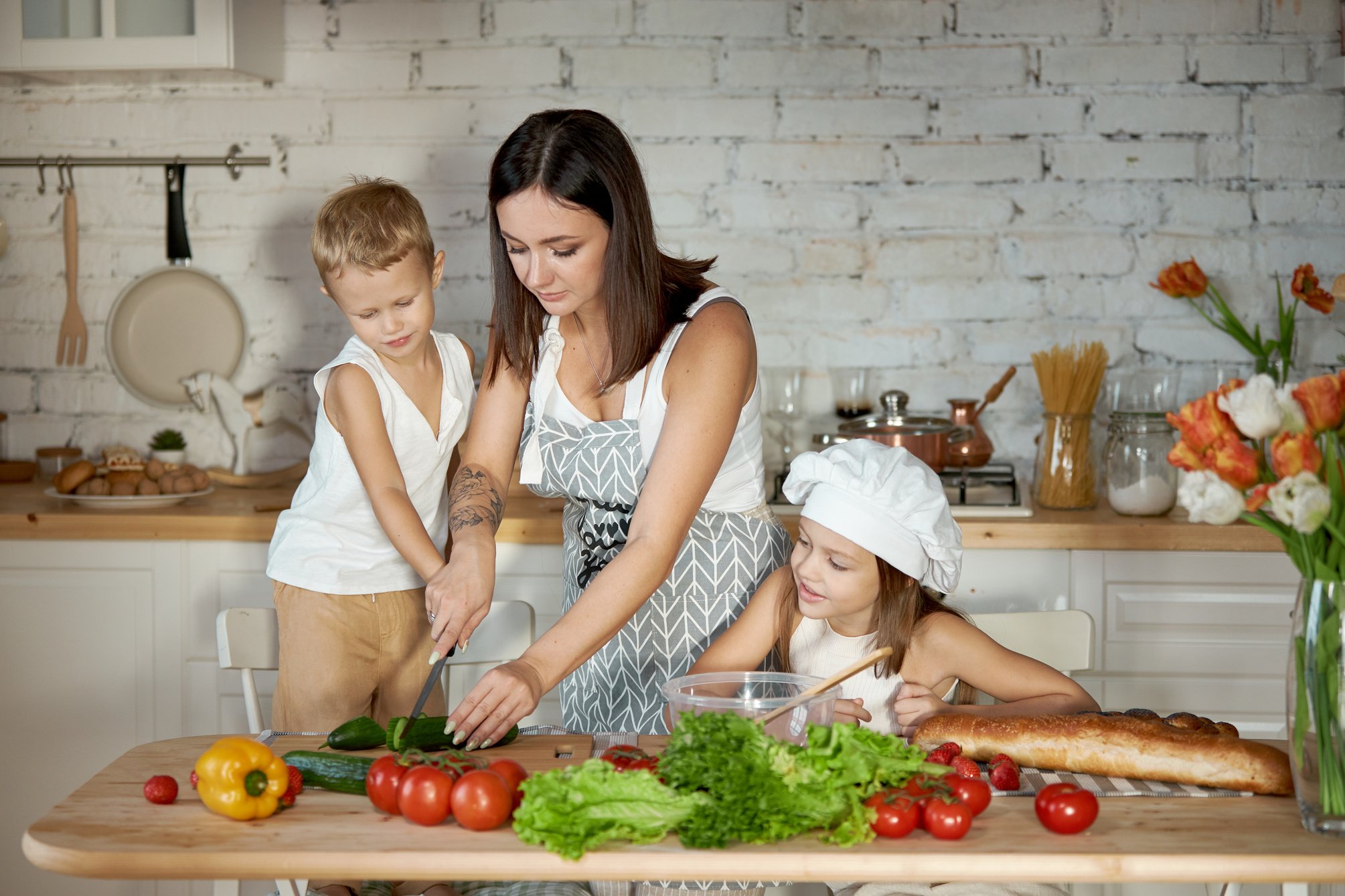 Mom cooks lunch with the kids. 